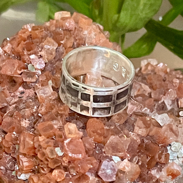 Silver ring with geometric design on a crystal rock background