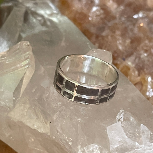 Silver ring with black pattern on a crystal background