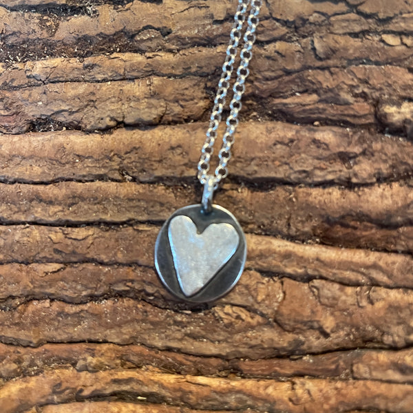 Silver heart-shaped pendant necklace on a wooden surface