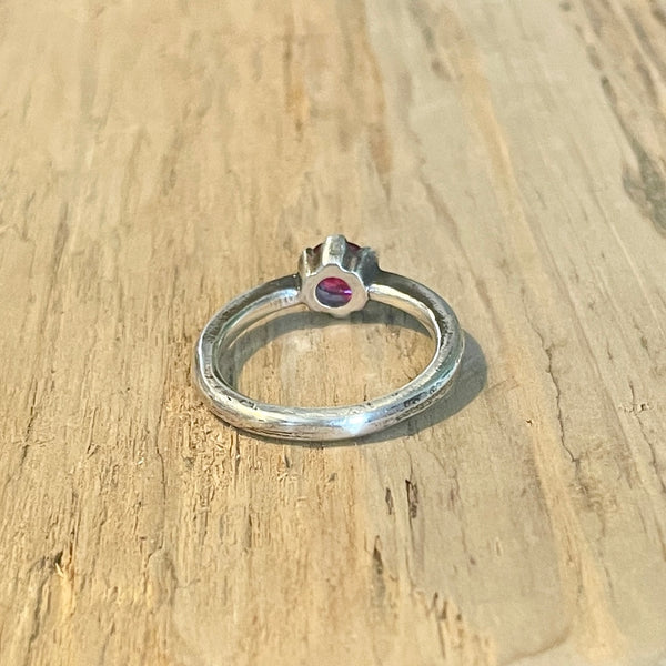 Bach view of silver ruby ring  on a wooden surface