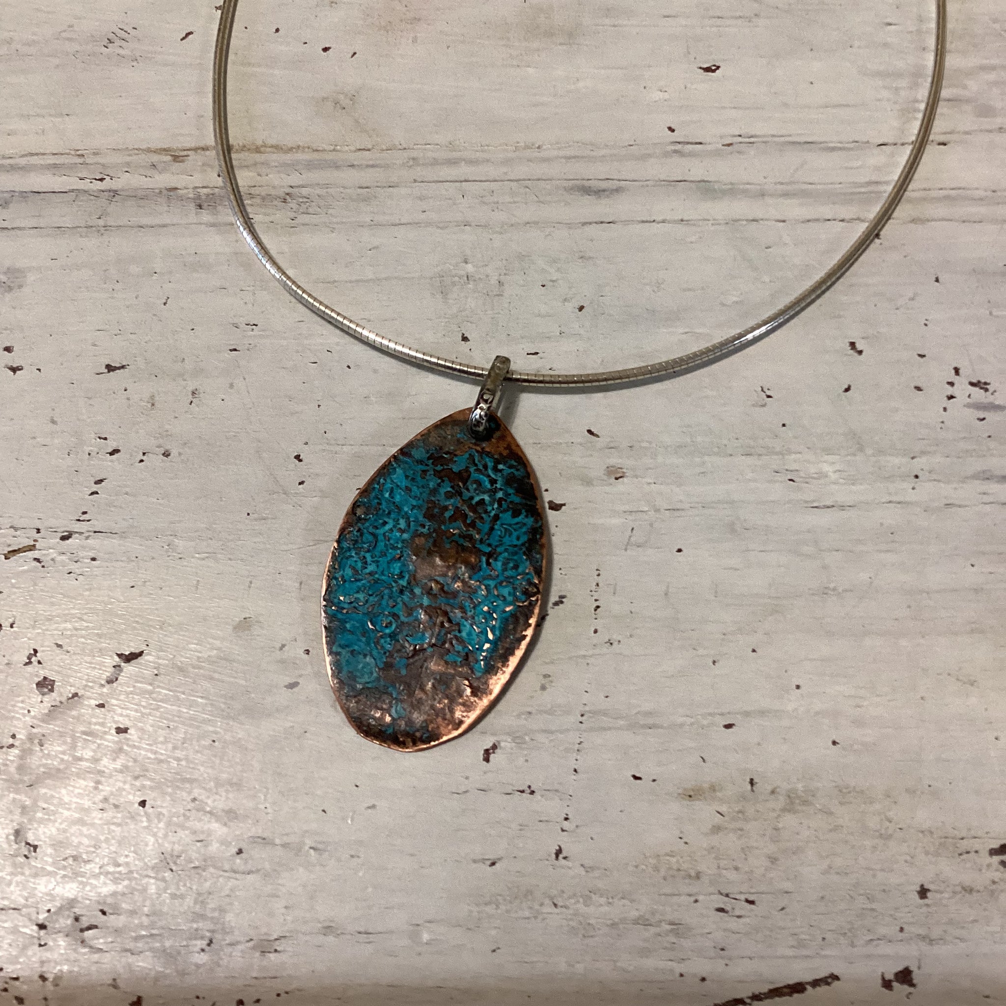 Oval copper pendant with patina